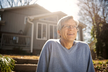 Happy man sitting at backyard during sunset - CAVF00828