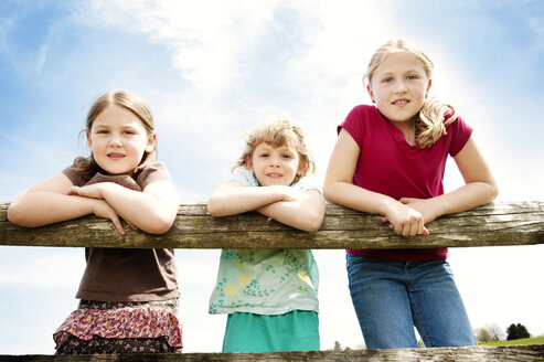 Portrait of girls standing on fence against sky - CAVF00835
