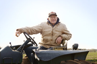Porträt eines selbstbewussten Landwirts, der einen Traktor gegen den Himmel fährt - CAVF00837