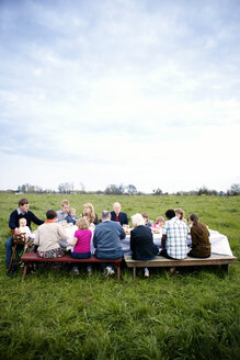 Familie und Freunde sitzen am Picknicktisch gegen den Himmel - CAVF00854