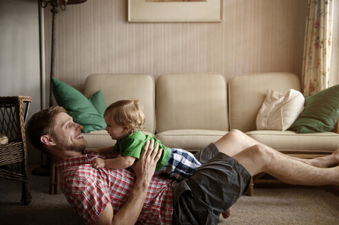 Seitenansicht eines Vaters, der mit einem kleinen Jungen auf einem Teppich spielt - CAVF00927