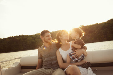 Woman carrying son while sitting with man in boat against clear sky - CAVF00938