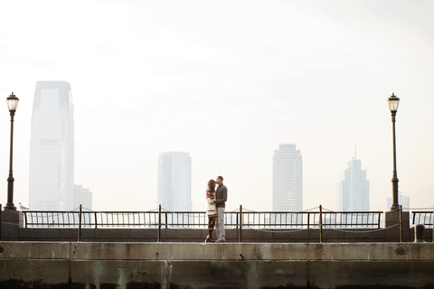 Junges Paar steht auf einer Fußgängerbrücke gegen den klaren Himmel, lizenzfreies Stockfoto