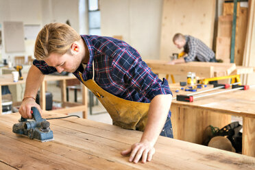 Male carpenter using tool to cut wood in workshop - CAVF01042