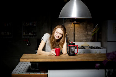 Junge Frau trinkt Kaffee in der Küche - CAVF01070