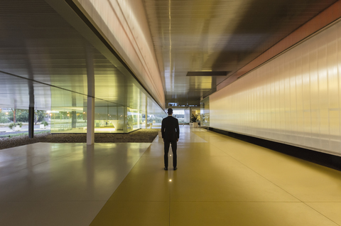 Geschäftsmann steht in beleuchtetem modernen Büro Lobby Korridor, lizenzfreies Stockfoto