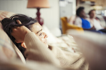 Junge Frau entspannt sich mit der Hand im Haar auf dem Sofa - CAIF04608