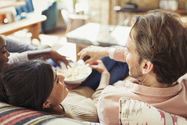 Freunde sehen fern und teilen sich Popcorn im Wohnzimmer - CAIF04635