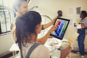 Freunde mit digitalem Tablet, die digitale Farbmuster betrachten, Wohnzimmer streichen - CAIF04687
