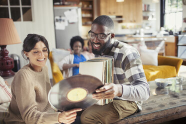 Paar sieht sich im Wohnzimmer Schallplatten an - CAIF04738