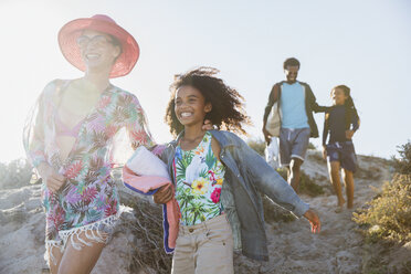 Lächelnde Familie beim Spaziergang am sonnigen Sommerstrand Hügel - CAIF04764