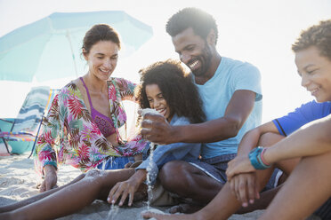 Familie spielt im Sand am sonnigen Sommerstrand - CAIF04768