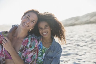 Portrait smiling, confident mother and daughter hugging on sunny, summer beach - CAIF04770
