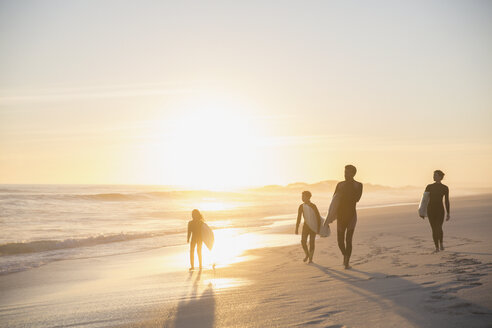 Silhouette Familie Surfer zu Fuß mit Surfbrettern auf idyllischen, sonnigen Sommer Sonnenuntergang Strand - CAIF04772