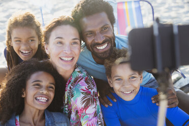 Smiling, happy multi-ethnic family taking selfie with selfie stick camera phone on beach - CAIF04773