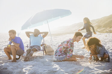 Eine multiethnische Familie entspannt und spielt am sonnigen Sommerstrand - CAIF04778