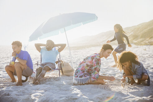 Eine multiethnische Familie entspannt und spielt am sonnigen Sommerstrand - CAIF04778