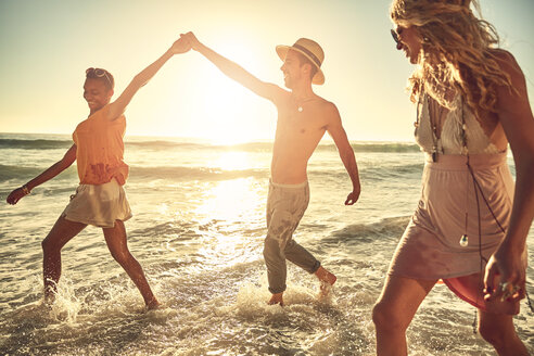 Verspielte junge Freunde, die im sonnigen Sommer in der Meeresbrandung planschen - CAIF04805