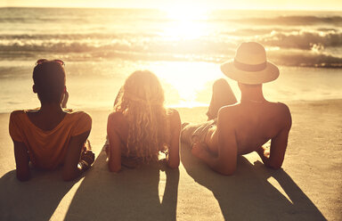 Carefree young friends relaxing on sunny summer sunset ocean beach - CAIF04812