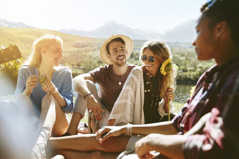 Lächelnde junge Freunde genießen ein Picknick in einem sonnigen Sommerpark - CAIF04813