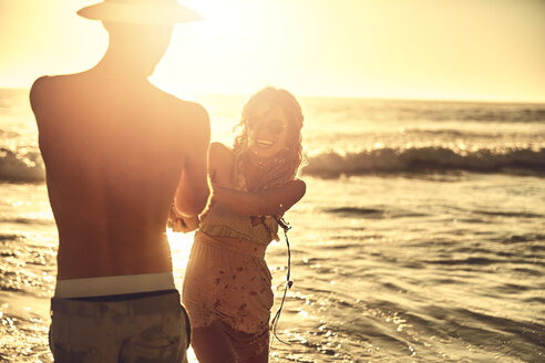 Playful junges Paar hält die Hände auf sonnigen Sommer Sonnenuntergang Ozean Strand - CAIF04821