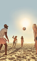 Junge Freunde spielen mit Strandball am sonnigen Sommerstrand - CAIF04825