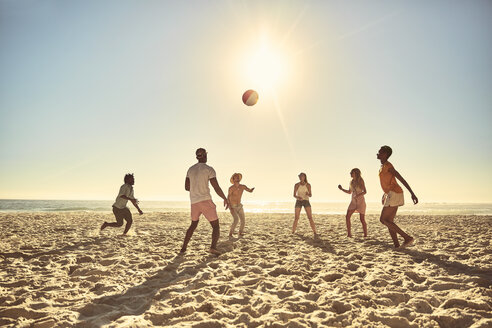 Junge Freunde spielen mit Strandball am sonnigen Sommerstrand - CAIF04827