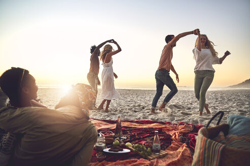 Junge Paare tanzen, genießen ein Picknick am Sommerstrand - CAIF04839