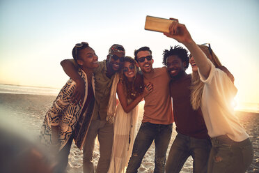 Young friends with camera phone taking selfie on sunny summer beach - CAIF04840