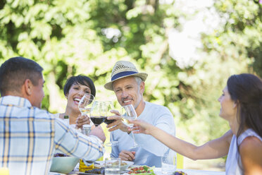 Friends toasting each other at table outdoors - CAIF04855