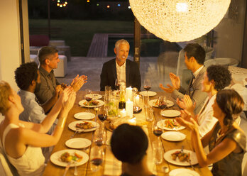 Freunde applaudieren einem Mann bei einer Dinnerparty - CAIF04865