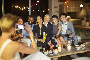 Woman taking picture of friends at party - CAIF04885