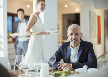 Mann lächelt am Tisch bei einer Dinnerparty - CAIF04888