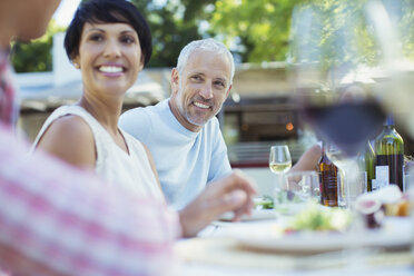 Couple smiling at table outdoors - CAIF04898