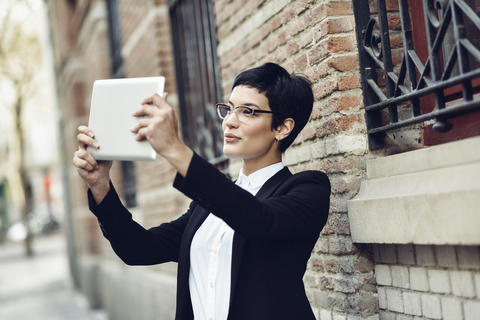Smiling young businesswoman taking selfie with tablet stock photo