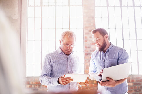 Businessmen with laptop and digital tablet working in sunny office - CAIF04925