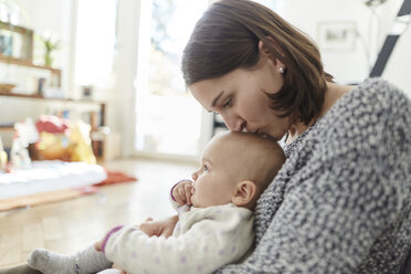 Mother kissing baby daughter on the head - CAIF04936