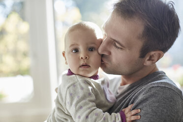 Portrait baby daughter being kisses on cheek by father - CAIF04937