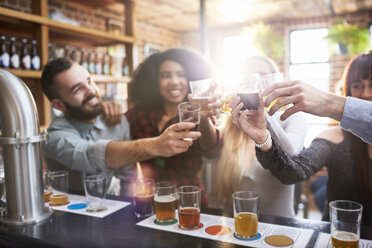 Friends beer tasting, toasting beer glasses in pub - CAIF04960