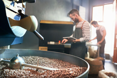 Männliche Kaffeeröster hinter dem Rösten von Kaffeebohnen - CAIF04969