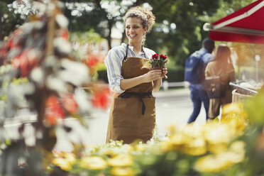 Lächelnde Blumenverkäuferin vor einem Blumenladen - CAIF04985