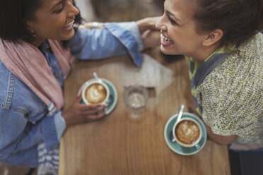 Young affectionate female friends drinking coffee and laughing in cafe - CAIF04998