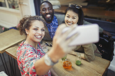 Lächelnde junge Freunde nehmen Selfie mit Kamera-Handy am Bürgersteig Cafe - CAIF05025