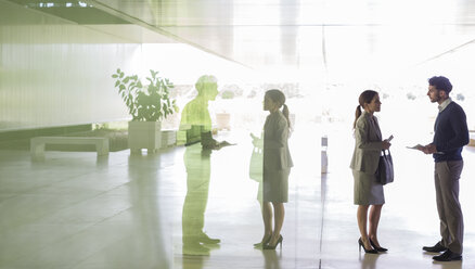 Business people talking in office lobby - CAIF05035