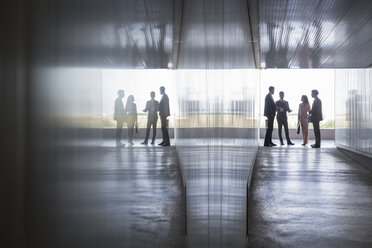 Silhouette von Geschäftsleuten im Gespräch im Bürokorridor - CAIF05038