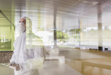 Wissenschaftler in sauberem Anzug mit digitalem Tablet am Fenster - CAIF05043