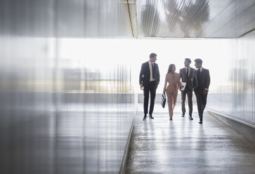 Business people walking and talking in office corridor - CAIF05053