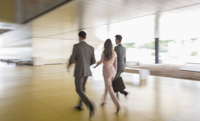 Business people walking in office lobby - CAIF05078