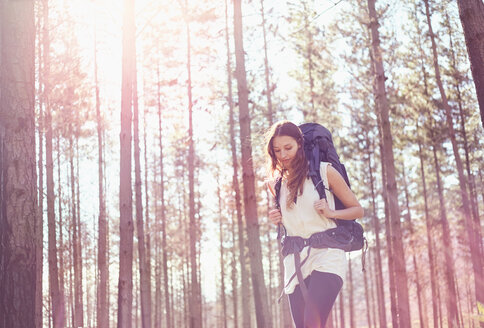 Junge Frau mit Rucksack beim Wandern im sonnigen Wald - CAIF05080