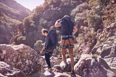 Junges Paar mit Rucksäcken beim Wandern über sonnige Felsen - CAIF05098